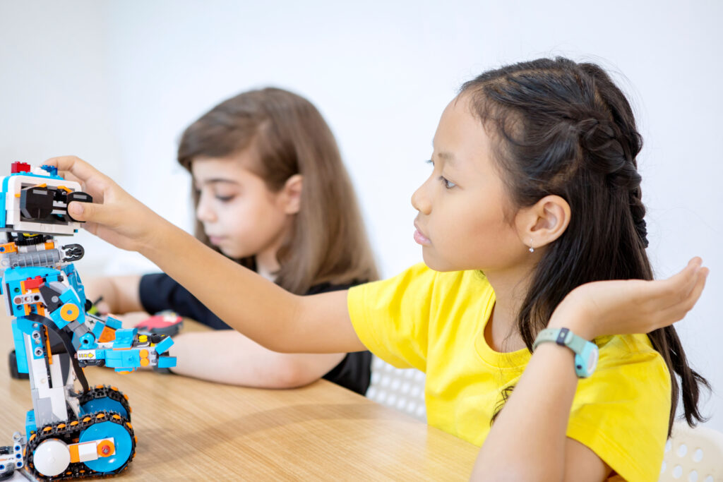 two little girl constructing a blocks robot in classroom